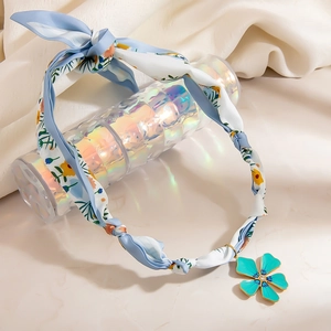 Blue floral fabric headband featuring a green flower pendant with gold-plated edges