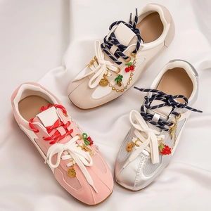 Detailed close-up of decorative metal chains and fruit charms on stylish mesh sneakers