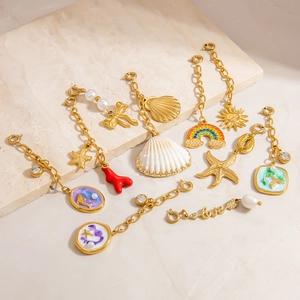 Macro shot of 18K gold plated starfish, shell, and sun pendants on a textured stone board