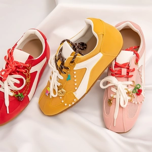 Detailed view of colorful retro sneakers with decorative pearl chains and cherry charms
