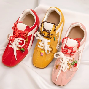 Close-up of beach-style steel pendants including cherry and pearl charms on colorful sneakers
