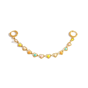 Macro detail of golden stainless steel ear chain with colorful enamel heart charms