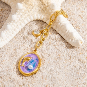 Detail of dolphin shell charm on sand for bikini accessories and DIY jewelry