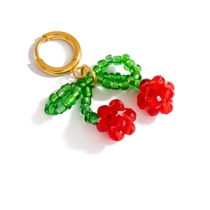 Detailed view of handmade cherry charm with red faceted beads and green leaf on gold ring