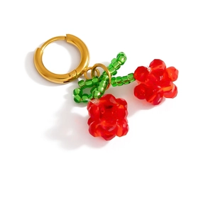 Close-up of golden cherry earrings with red crystal beads and green leaf beadwork