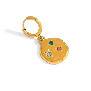 Macro detail of vintage gold earring with hammer textured surface and colored zircon stones