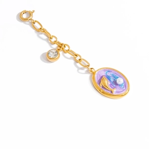 Macro detail of golden dolphin charm with purple enamel and small pearl on a bikini clasp