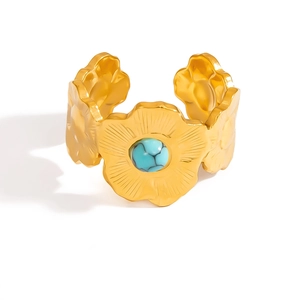 Dettaglio ravvicinato di un anello a fiore dorato con turchese e petali a trama radiale