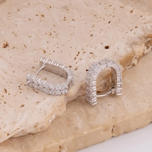 Détail de boucles d'oreilles en U argentées avec double rangée de zircons sertis pavé