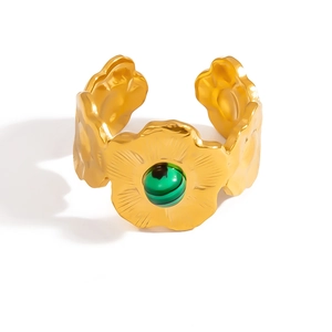 Dettaglio anello fiore dorato con pietra verde malachite e finitura martellata