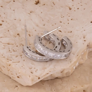 Détail macro de boucles d'oreilles C en argent avec oxydes de zirconium sertis