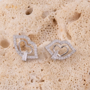 Vue macro de boucles d'oreilles argentées en forme de lèvres avec cœur évidé et zircon