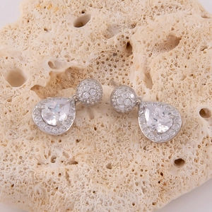 Macro de boucles d'oreilles en argent avec cristaux pavés sur fond de corail texturé