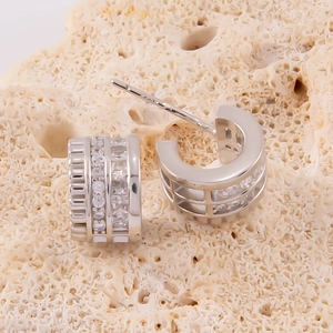 Vue macro de boucles d'oreilles créoles argentées serties de rangées de zircons