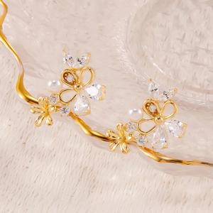 Detailaufnahme goldener Blumen- und Schmetterlingsohrringe mit Perlen und Zirkonia
