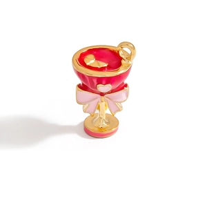 Detailed close-up of a golden cocktail glass pendant with red enamel and a pink bow