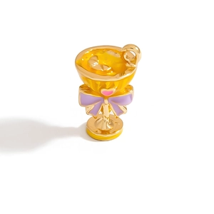 Detailed view of a gold-plated cocktail cup charm with yellow enamel and pink heart detail