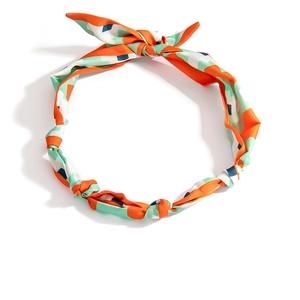 Dettaglio della collana foulard in seta con motivi paisley arancioni e verde menta