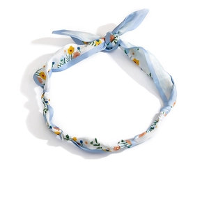 Dettaglio del foulard in seta floreale con trama satinata lucida e bordi azzurri rifiniti