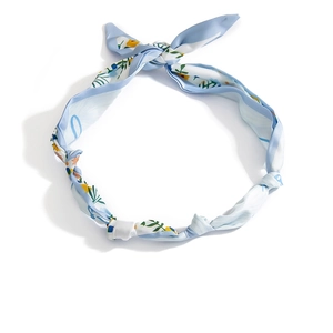Dettaglio della collana foulard in seta celeste con motivi floreali e texture liscia
