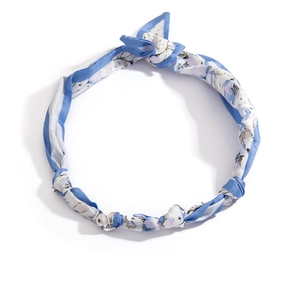 Dettaglio della fascia per capelli in seta blu con stampa floreale e design a nodo