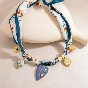 Bohemian silk scarf necklace with heart charms and natural stone pendants on a ceramic stand