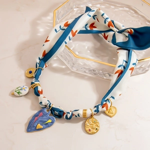 Floral silk scarf necklace with 18K gold plated heart and star pendants on marble