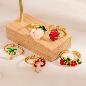 Detail view of five fruit themed 18K gold plated rings on a wooden display stand