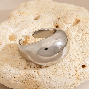Polished silver irregular twisted wide open ring displayed on white coral stone