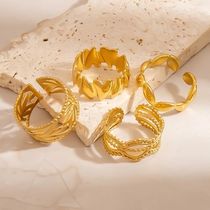 Detail view of four gold-plated minimalist rings featuring heart and leaf designs