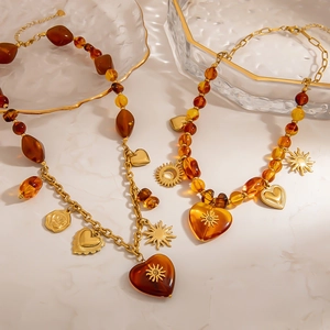 Retro amber bead necklace and bracelet with gold heart and sun pendants on marble