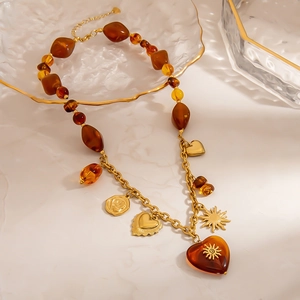 Vintage stainless steel sun heart necklace with amber beads and gold pendants on marble
