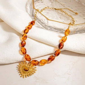 Amber resin beaded necklace with golden sun heart pendant on premium white fabric