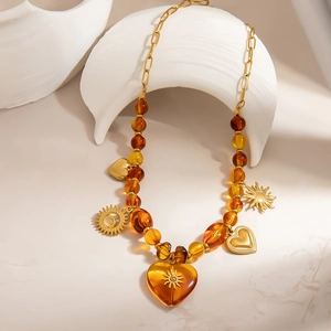 Boho amber resin bead necklace with 18K gold plated heart pendant on minimalist white stand