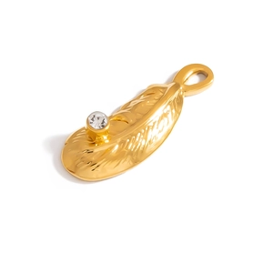 Detailed macro view of a golden feather pendant with a sparkling white crystal inlay