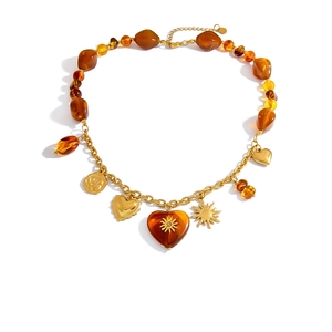 Bohemian amber resin beaded necklace with golden heart and sun pendants on white background