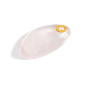 Macro shot of leaf-shaped white resin guasha tool with a gold ring detail on a white background
