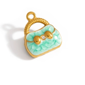 Detailed macro view of gold-plated handbag pendant with green enamel and crystal