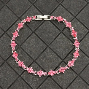 Gros plan du bracelet tennis à fleurs en strass roses sur support en cuir noir