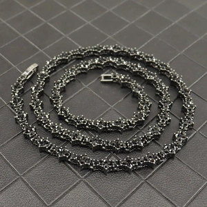 Macro view of gunmetal tennis necklace featuring black stones and cross petal links