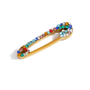 Detailed macro view of gold-plated safety pin charm encrusted with colorful rhinestones
