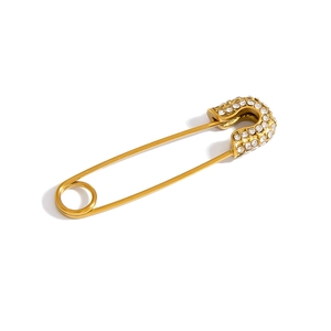 Macro detail of a golden safety pin pendant with sparkling rhinestones on white backdrop