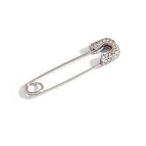 Close-up of a silver safety pin brooch with white rhinestones on white background