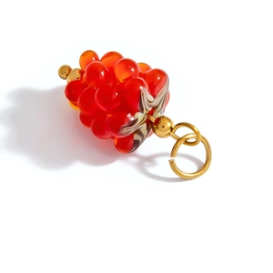 Macro detail of a red grape-shaped resin charm with gold-plated metal ring connector