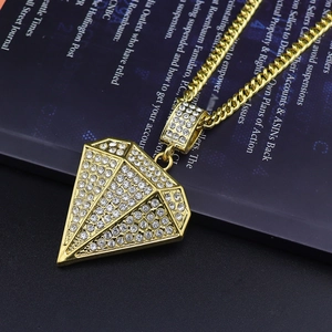 Gros plan du pendentif hip hop serti de strass blancs et chaîne cubaine dorée