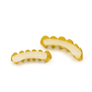 Detailed view of hip hop gold teeth grillz set with clear silicone fixing bars on white background