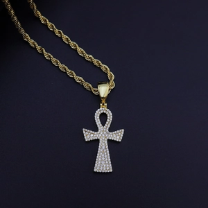 Gros plan du pendentif croix Ankh dorée avec zircons micro-pavés et chaîne torsadée