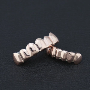 Macro shot of rose gold hip-hop grillz set featuring a polished mirror finish on black leather