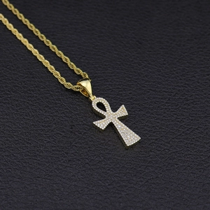 Gros plan du pendentif croix Ankh doré avec zircons micro-pave et chaîne torsadée