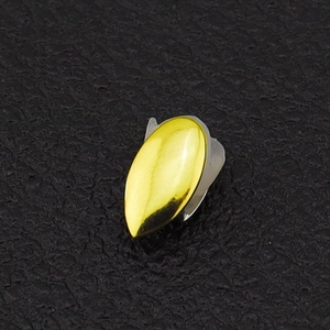 Macro detail of a single gold plated hip hop fang grillz on black leather background